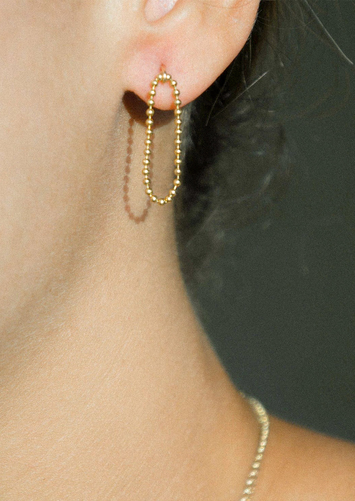 A pair of gold post back earrings with ball chain loop front.