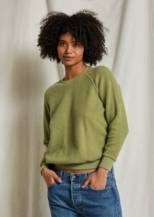 A woman wearing a reverse fleece sweatshirt in oil green.