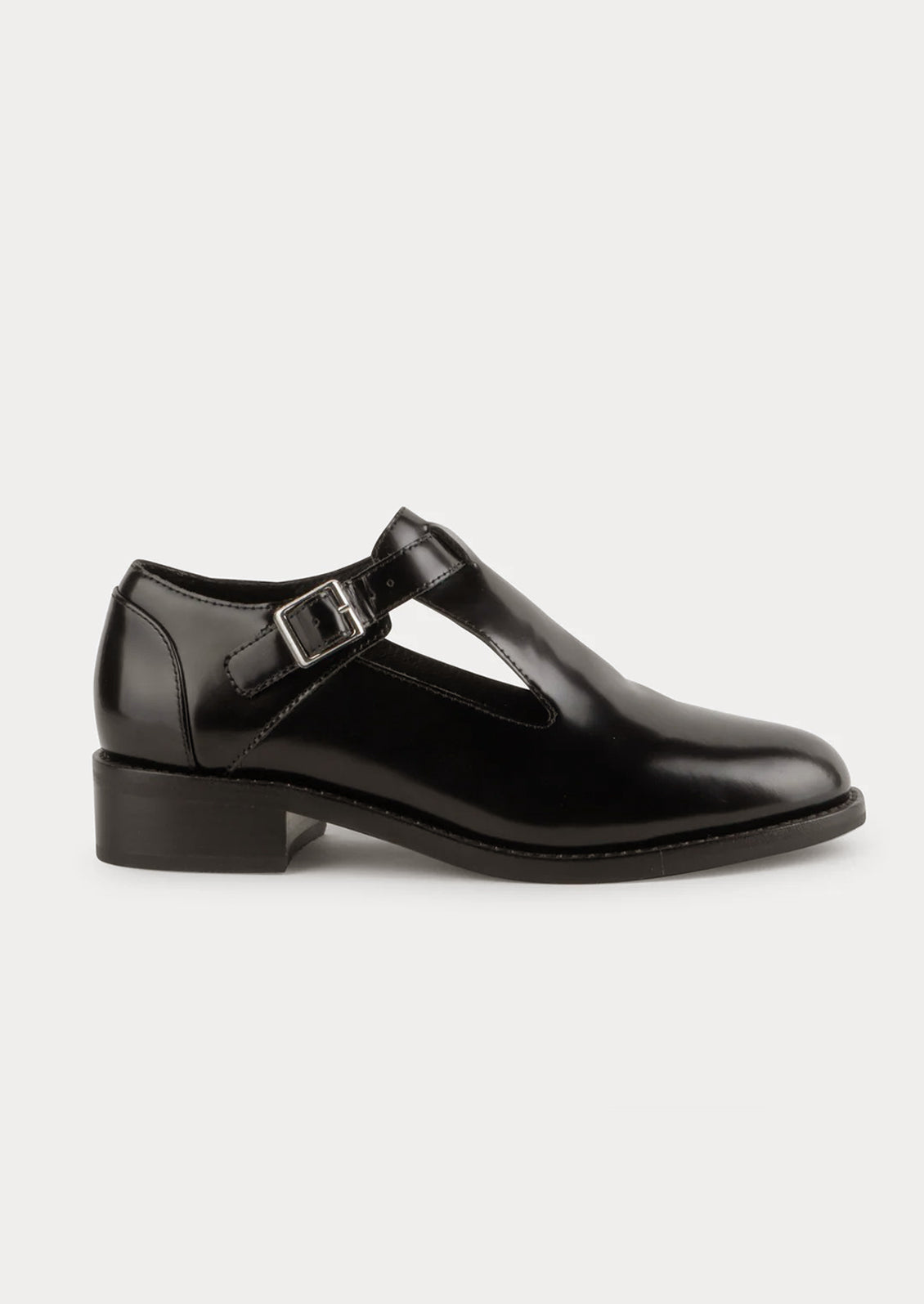 A pair of leather shoes in black with high vamp and buckle strap at ankle.