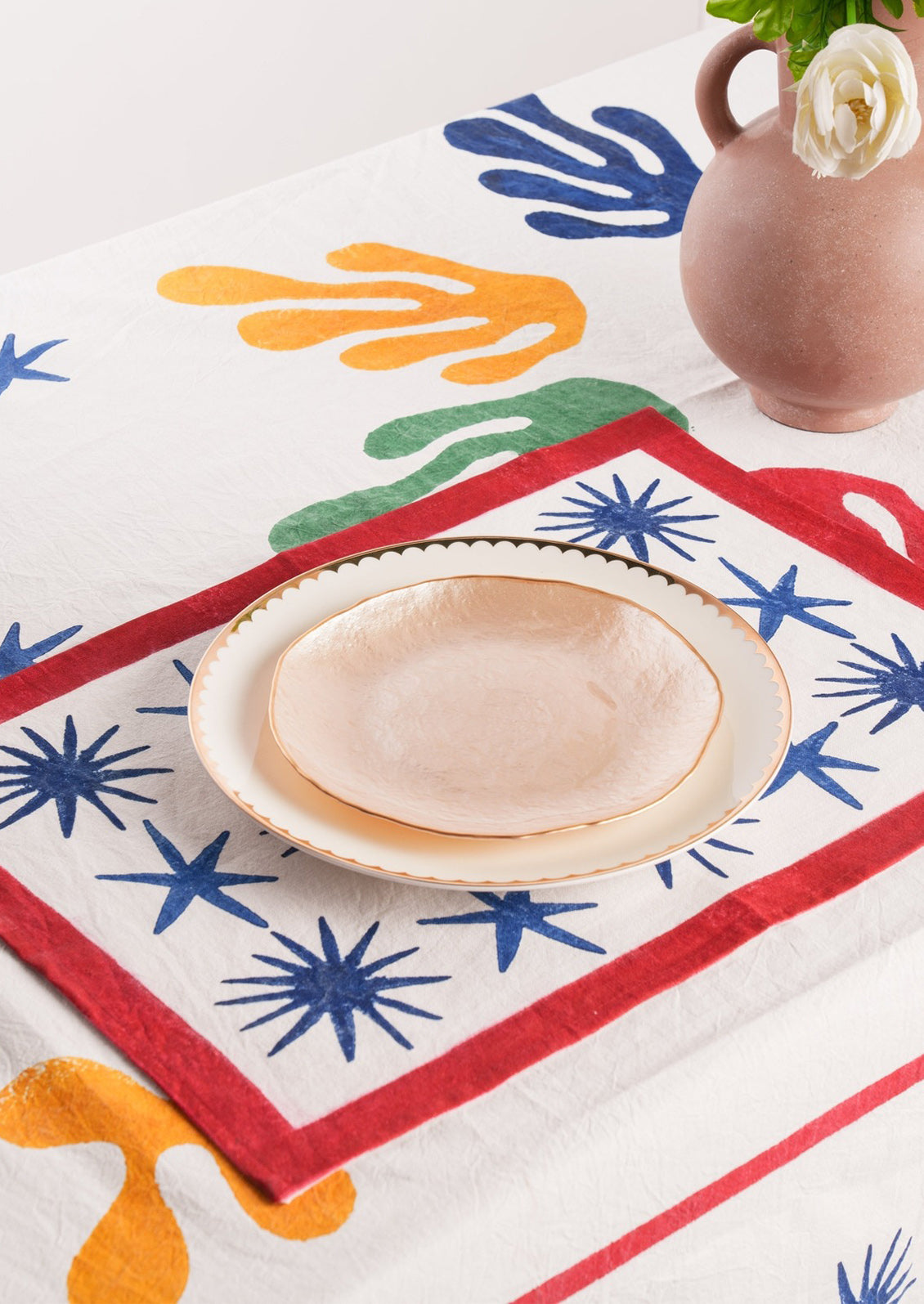 A block printed placemat in white with blue stars and red border.