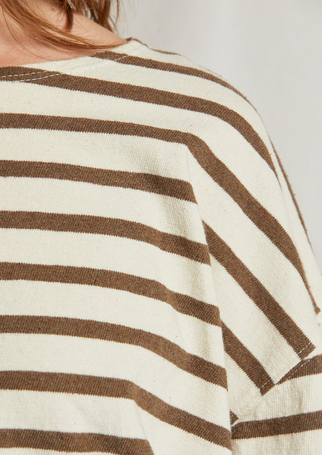 A woman wearing a long sleeve t-shirt in natural cotton with brown stripes.