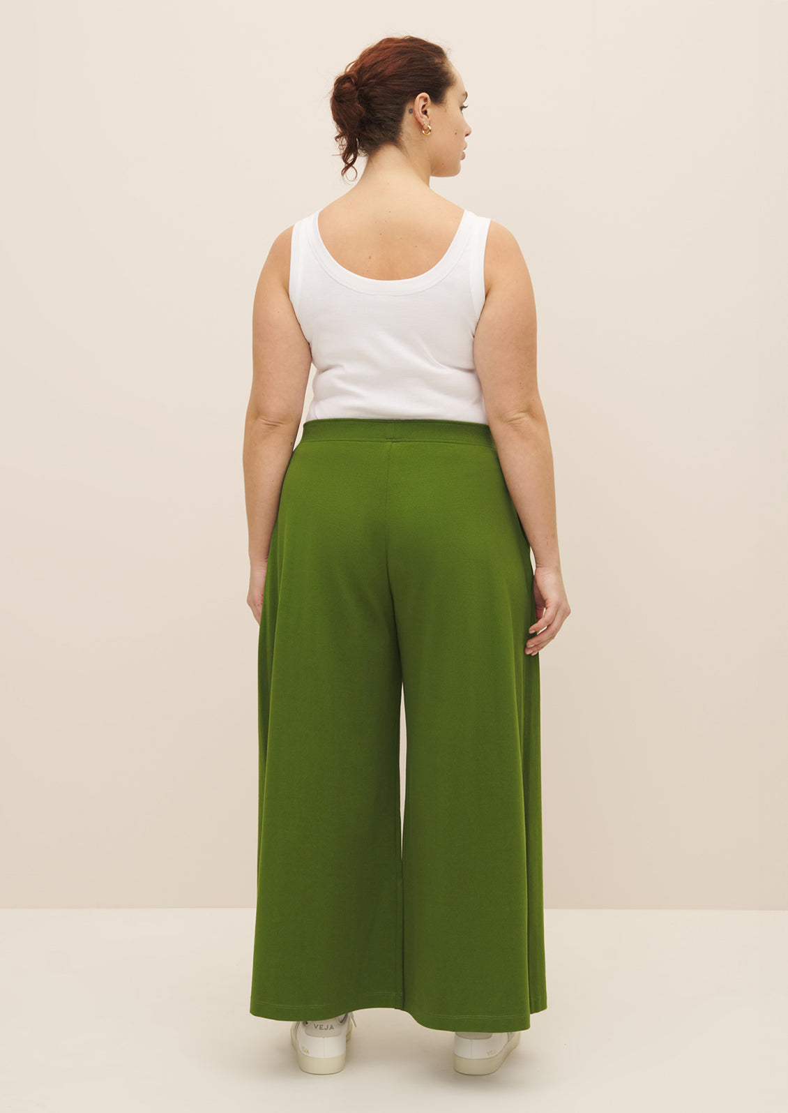 A woman wearing a pair of flowy, wide leg green pants.