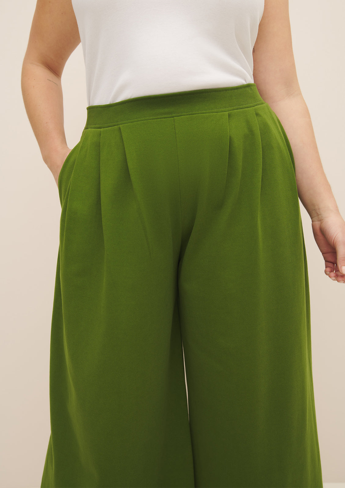 A woman wearing a pair of flowy, wide leg green pants.