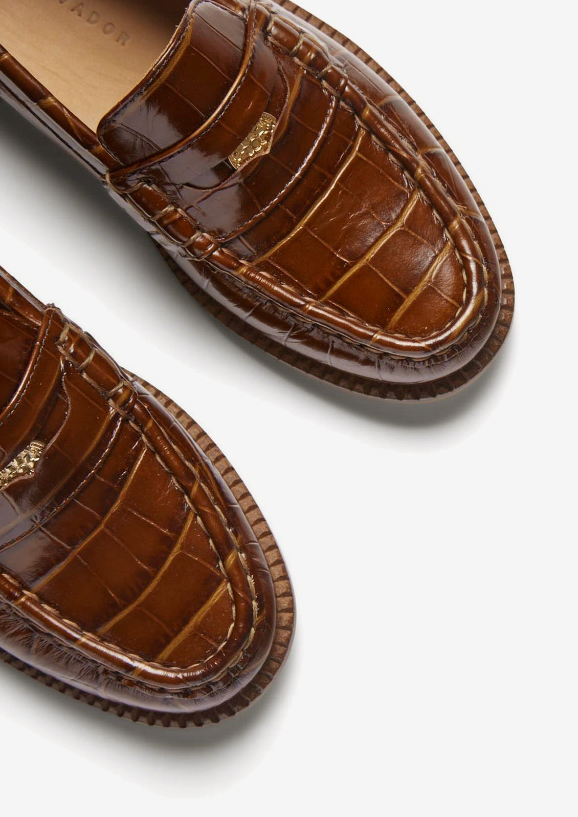 A pair of penny loafers in brown croc embossed leather.