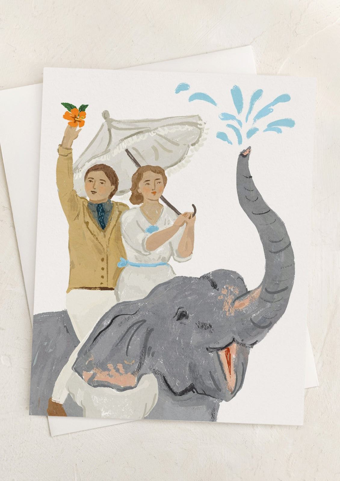 A card with illustration of two people dressed in fancy attire, riding on top of an elephant.