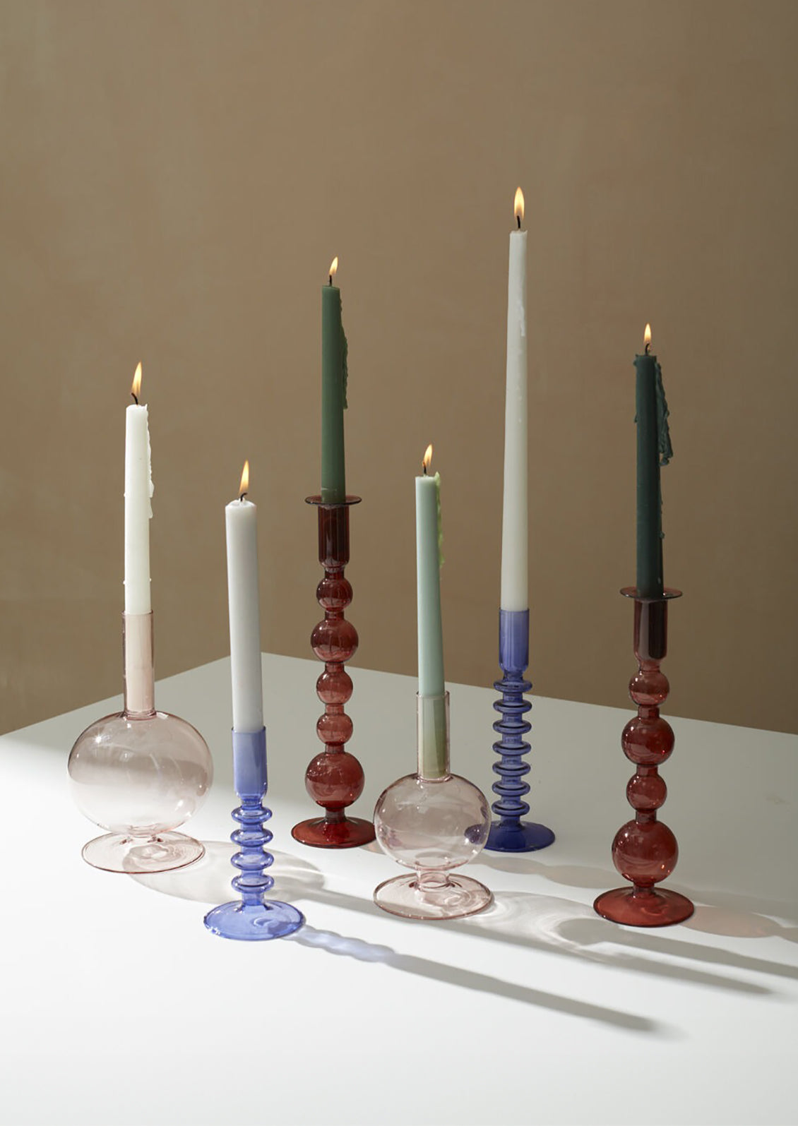 Assorted glass candle holders on table setting.