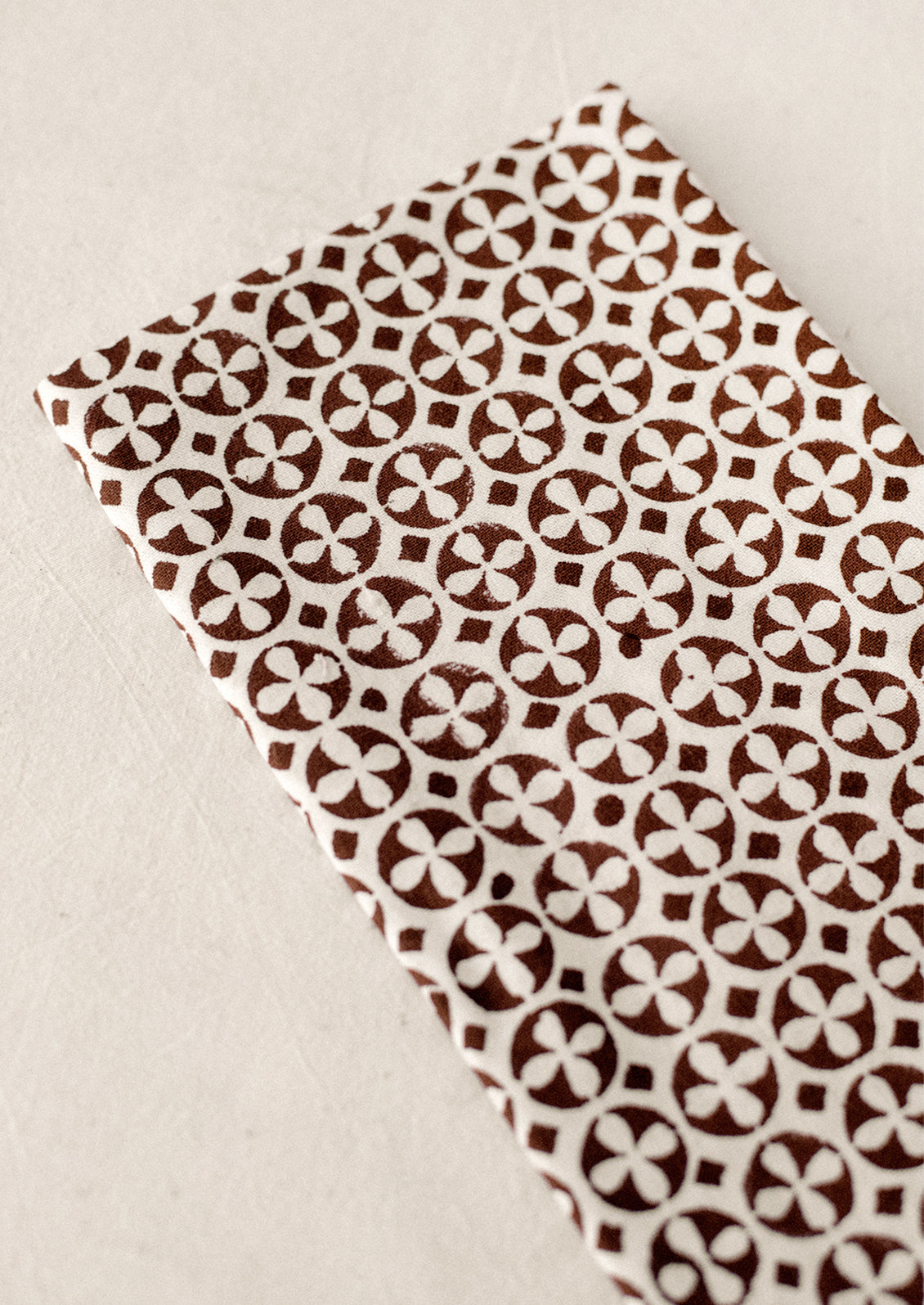 A pair of napkins with geometric circular cross pattern in brown and white.