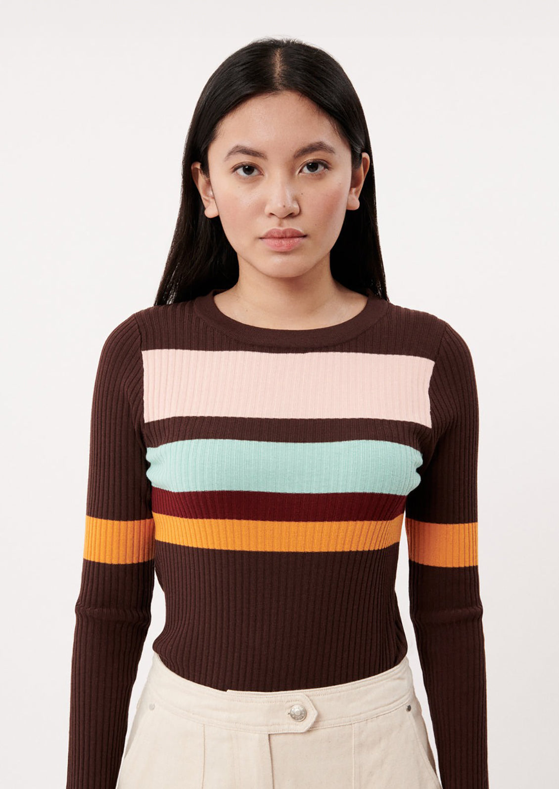 A woman wearing a brown form fitting sweater with multicolor stripes.