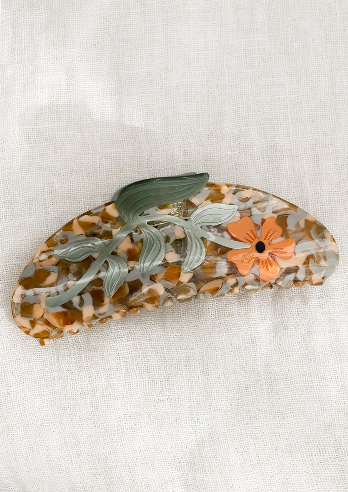 A speckled acetate hair claw with orange flower.