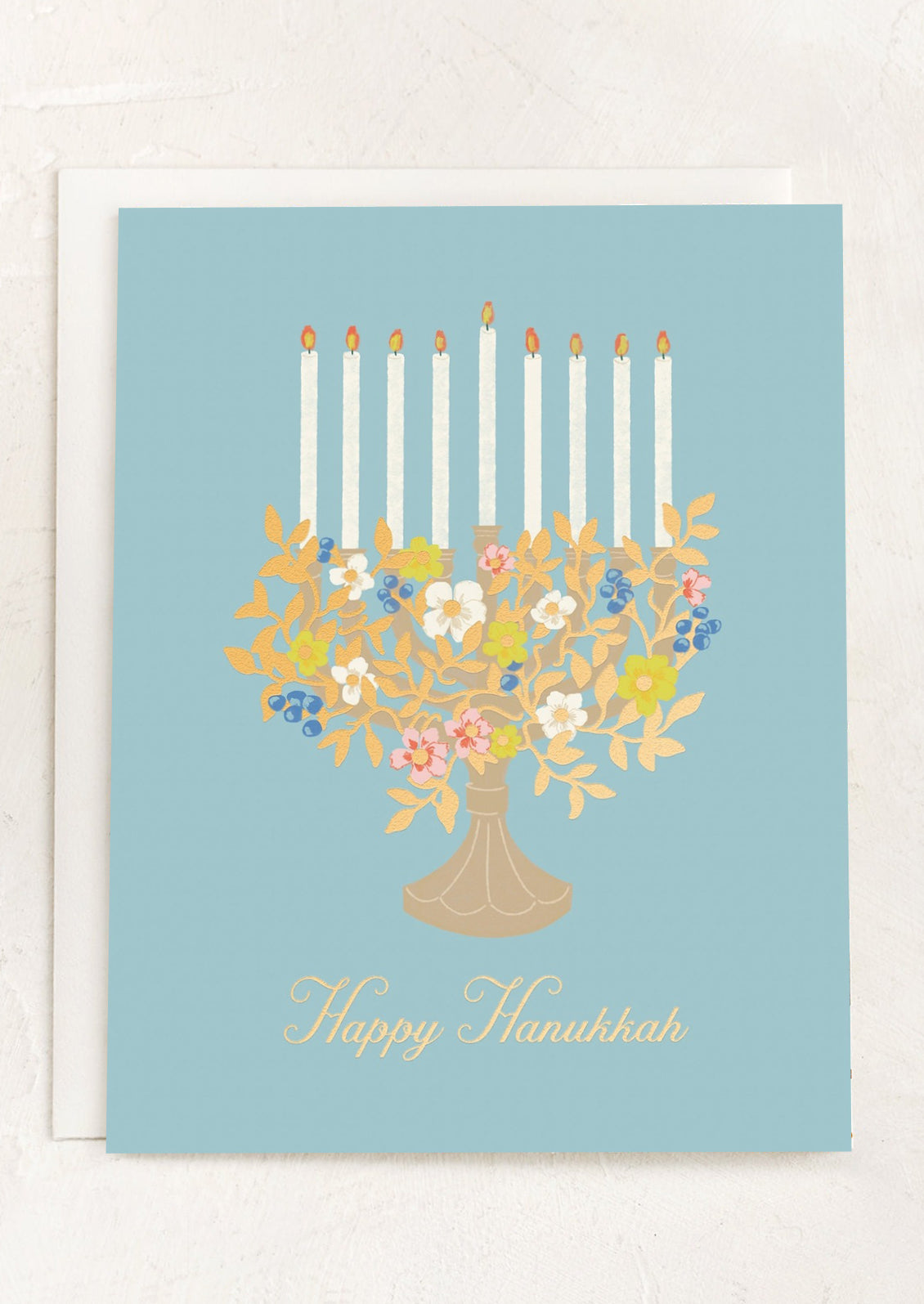 A blue card with image of floral menorah, text reads "happy hanukkah".