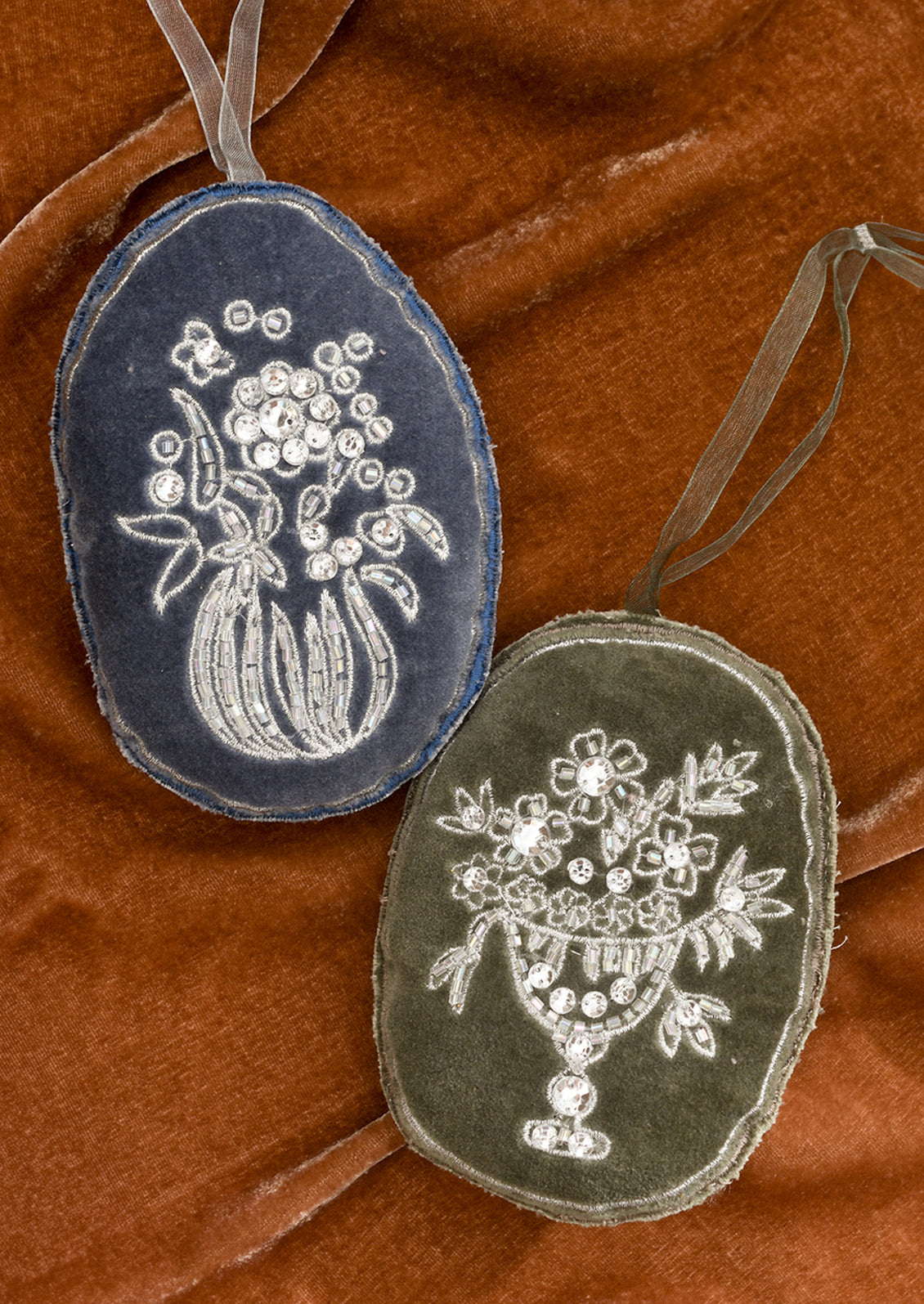 Oval shaped velvet ornaments with silver floral embroidery.