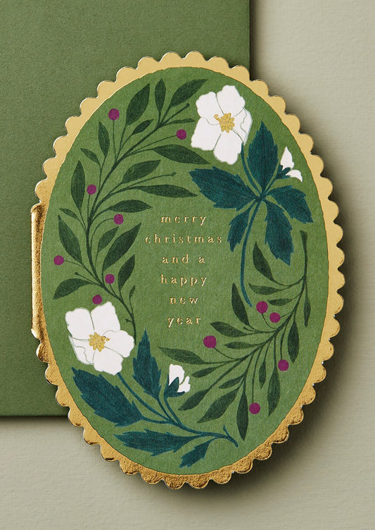 A scalloped edge oval shaped card reading "Merry Christmas and A Happy New Year".