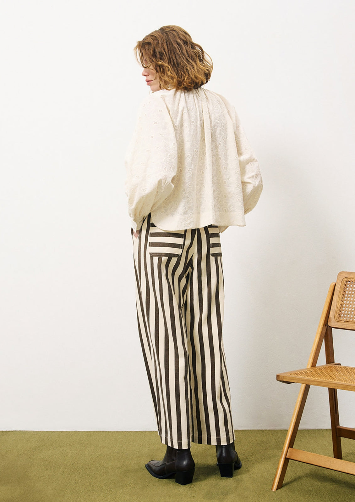 A woman wearing a cream cotton blouse with tonal paisley embroidery.