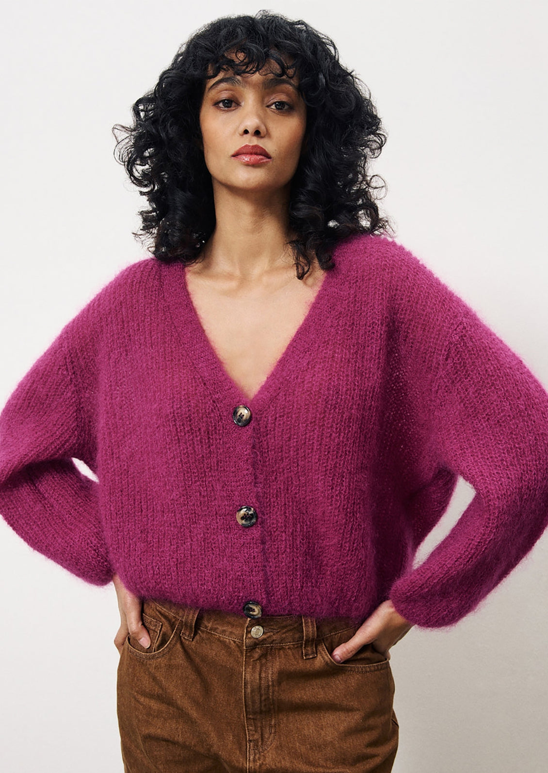 A woman wearing a vibrant magenta mohair v-neck cardigan.