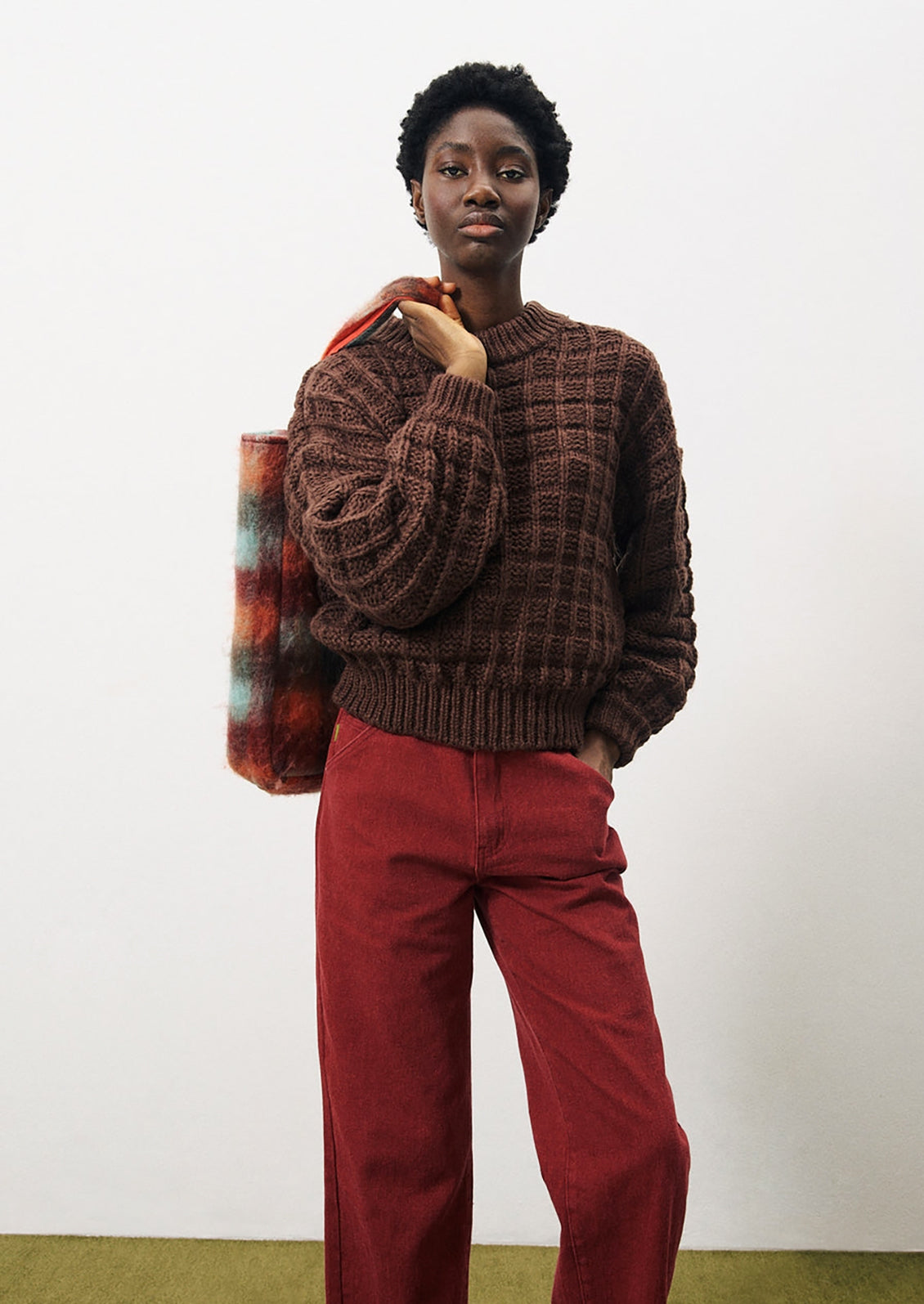 A person wearing a chunky waffle knit sweater in brown.