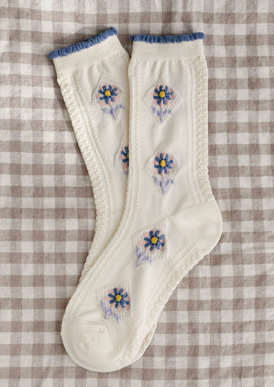 A pair of cream socks with pink, yellow, blue and lavender floral pattern.