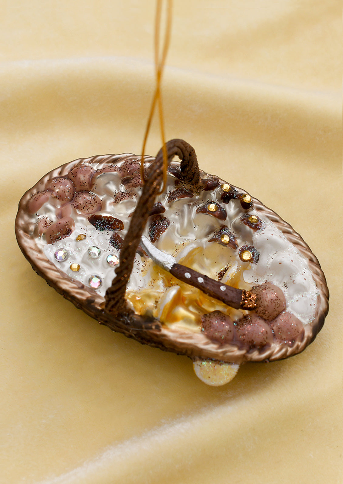 A glass ornament of a foraging basket holding assorted mushrooms.