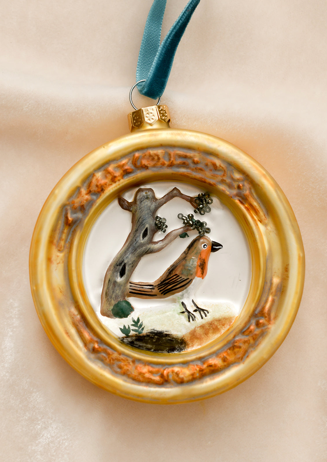 A glass ornament of a robin in gold frame.