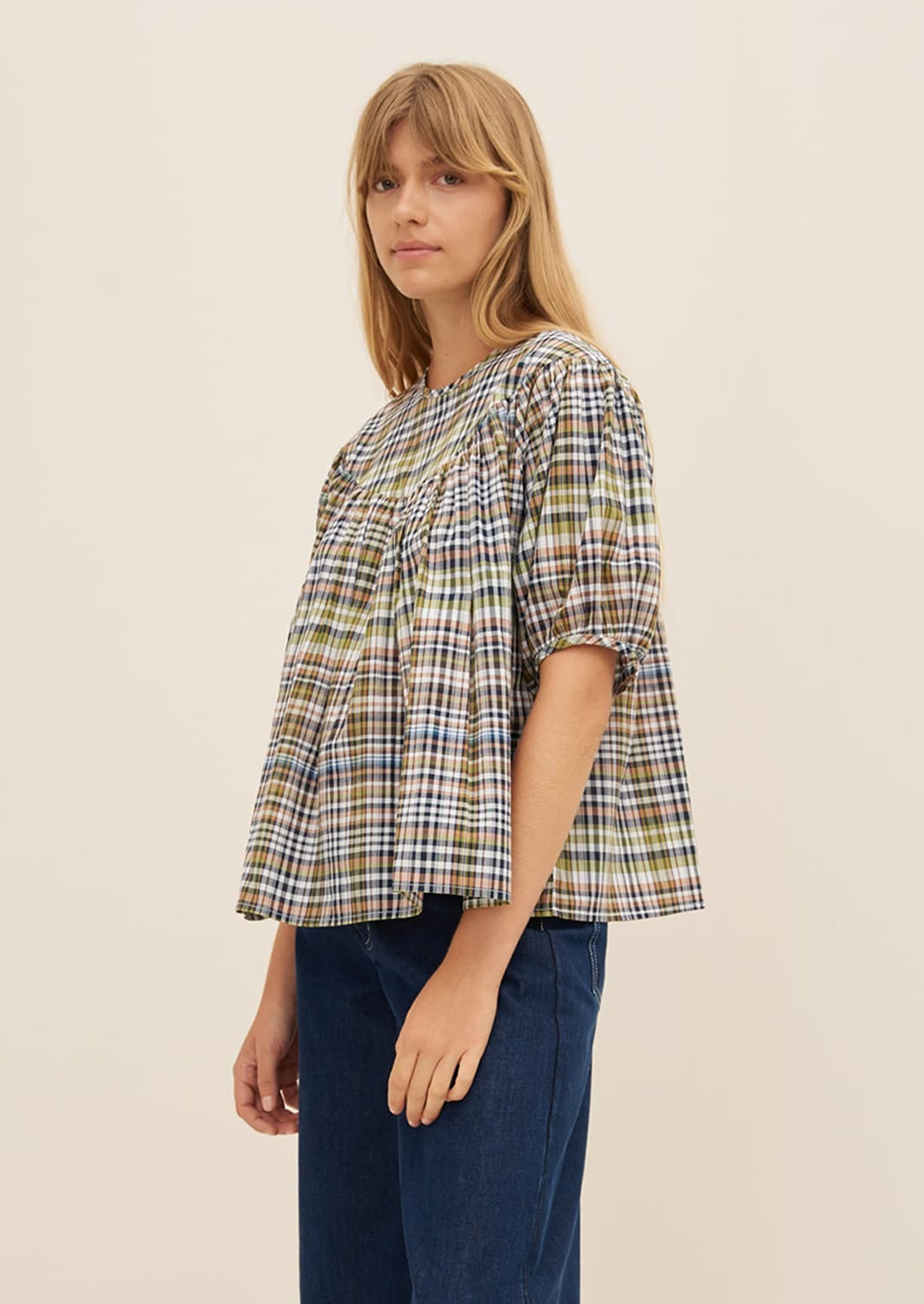 A woman wearing a plaid blouse with ruching details.