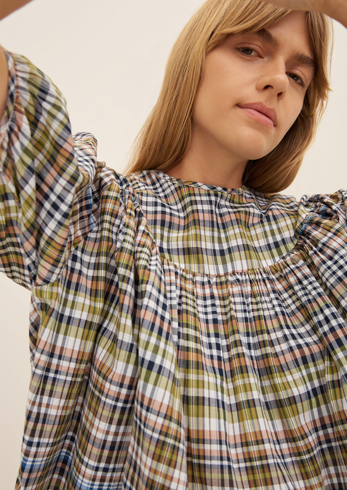 A woman wearing a plaid blouse with ruching details.