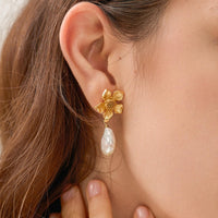 1: A pair of earrings with three dimensional gold flower post and dangling baroque pearl.