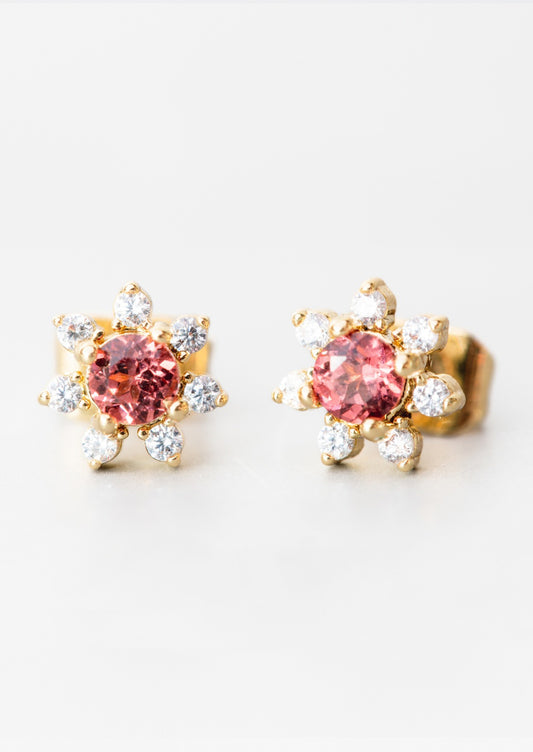 A pair of flower shaped studs with gemstone and crystal in red.