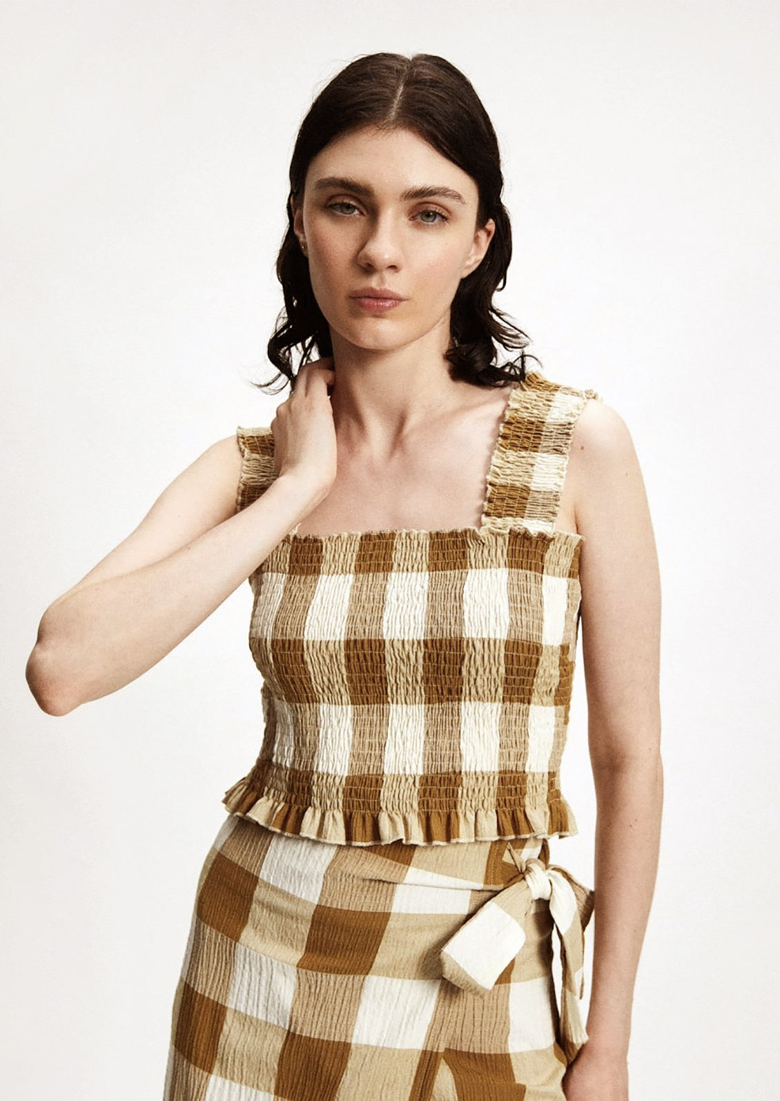 Woman wearing brown-and-white gingham smocked top and matching skirt. 