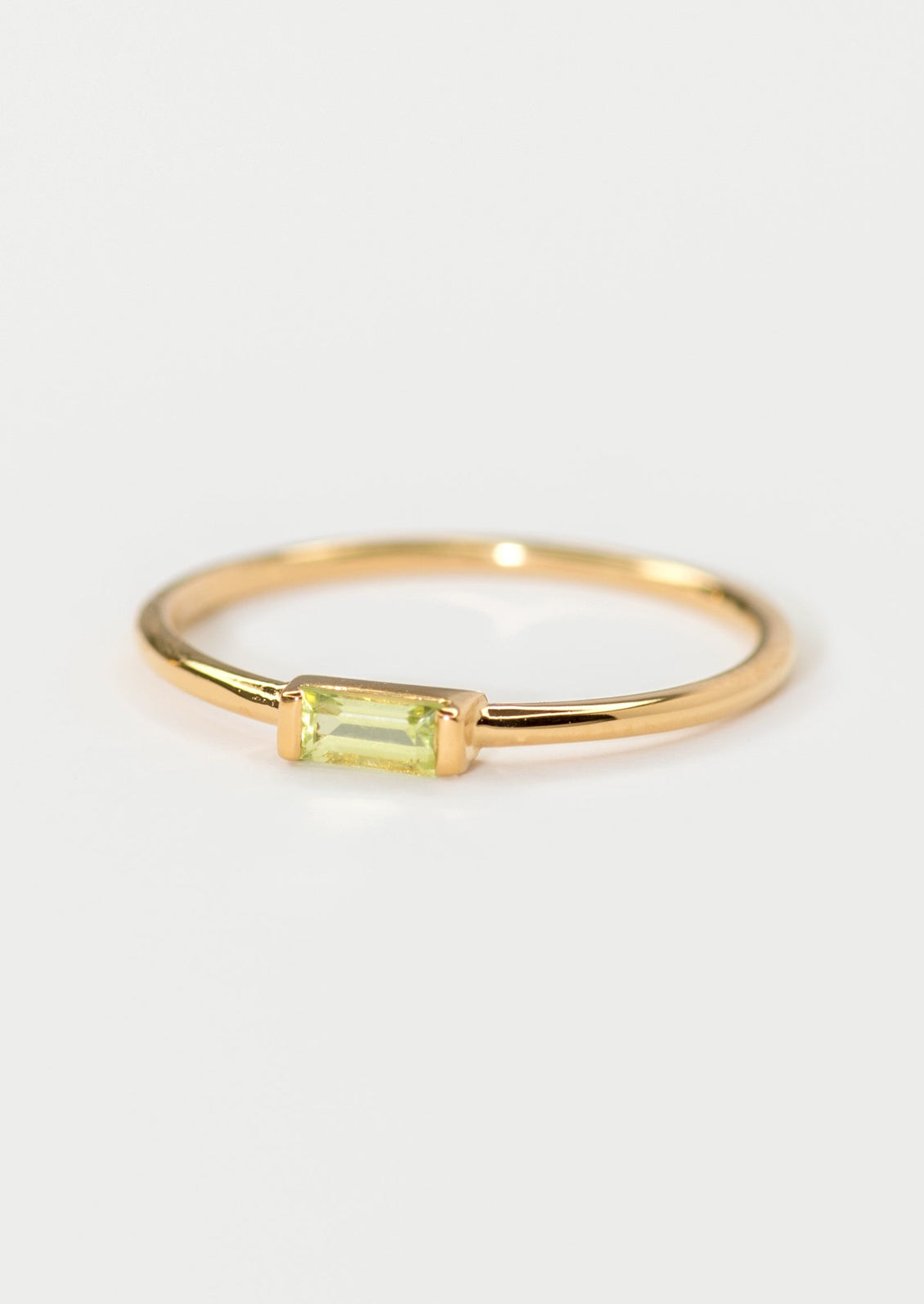 A gold ring with slim baguette stone in peridot.