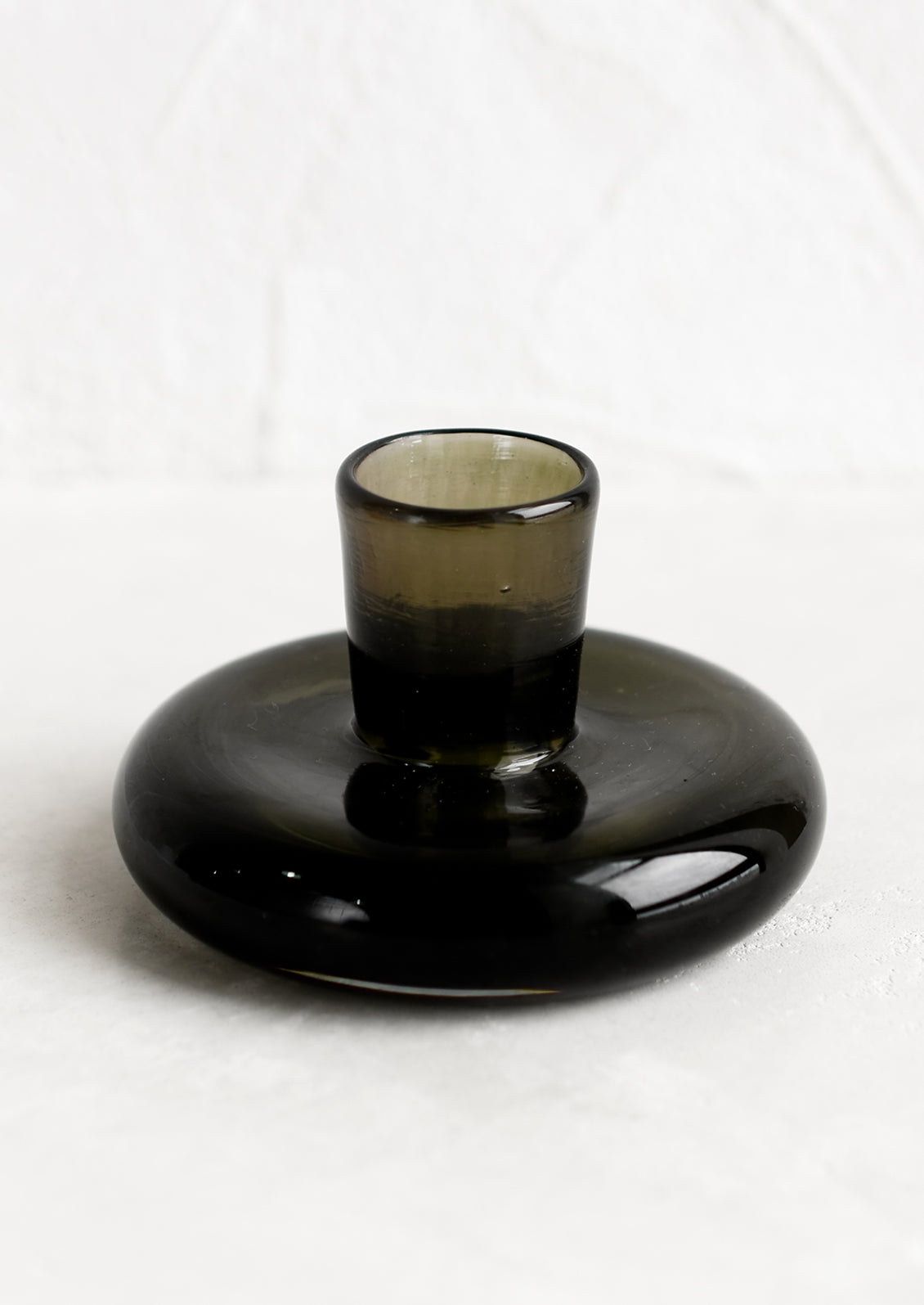 A glass taper candle holder in dark green (spruce).