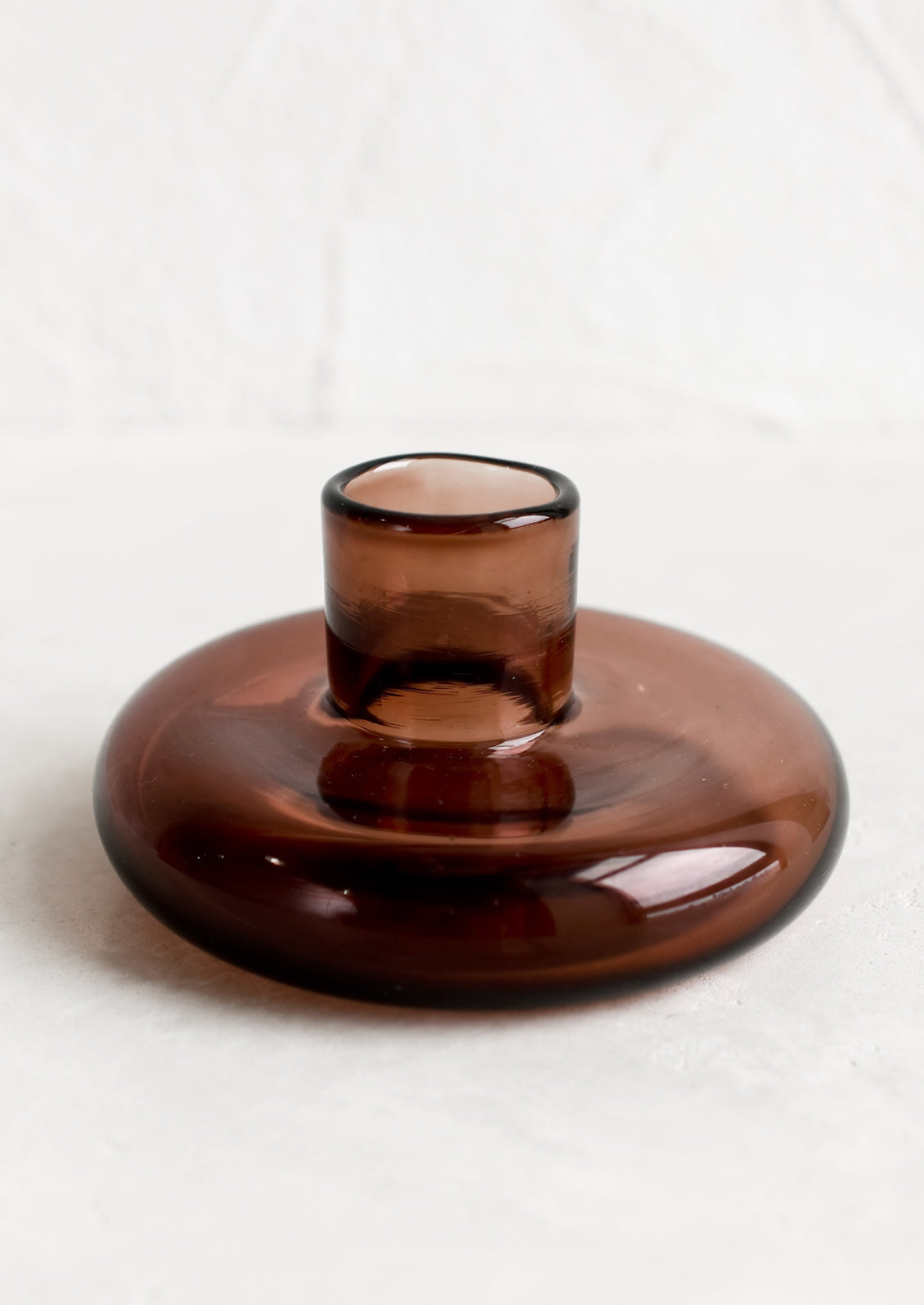 A glass taper candle holder in rosewood.