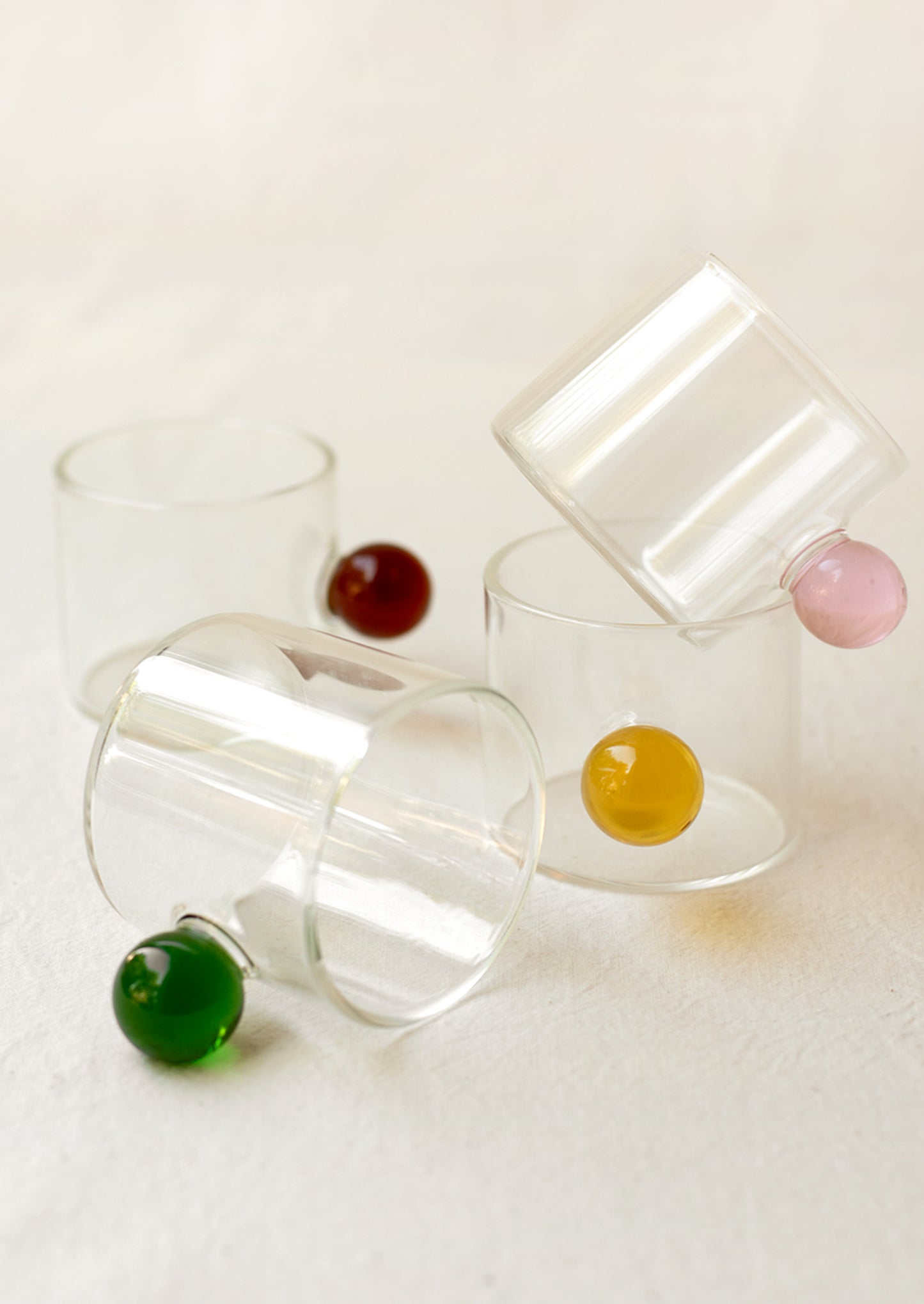 An assortment of clear glass espresso cups with colorful knob handles.