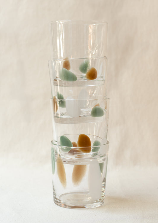 A stack of clear glass tumblers with mint, brown and white speckle pattern.