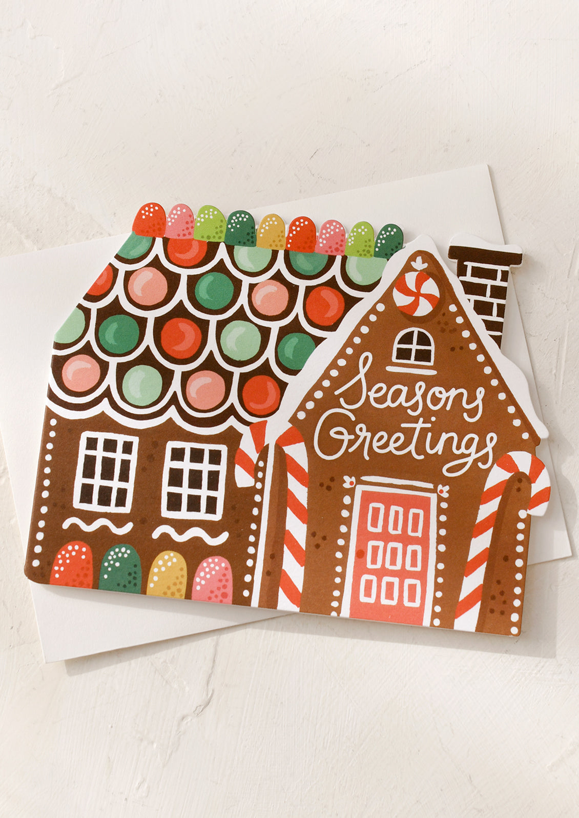 A diecut card in shape of gingerbread house, text reads "Seasons Greetings".