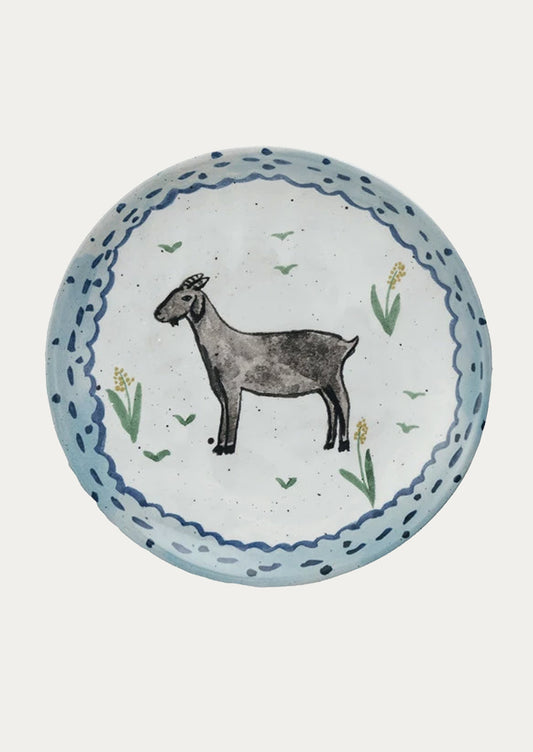 A small ceramic plate with hand painted imagery of goat with yellow flowers.