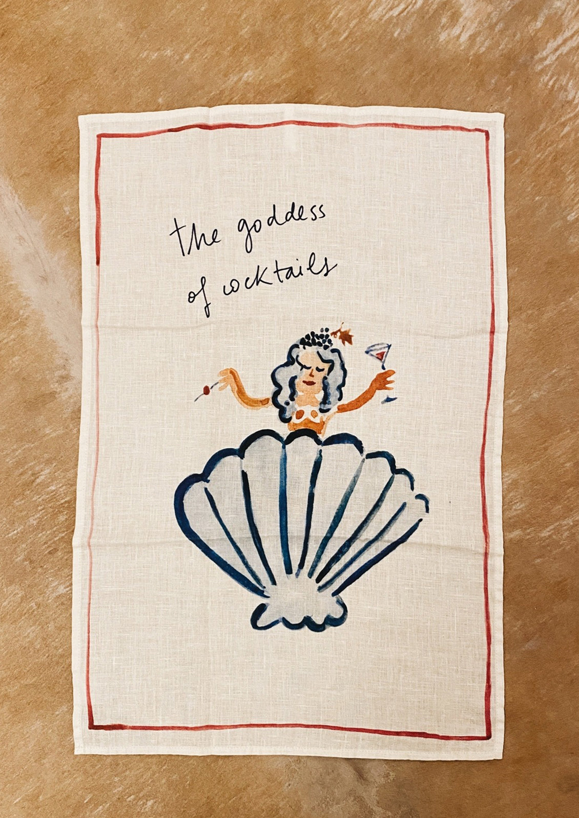 A white linen tea towel with Goddess of Cocktail graphic and text.