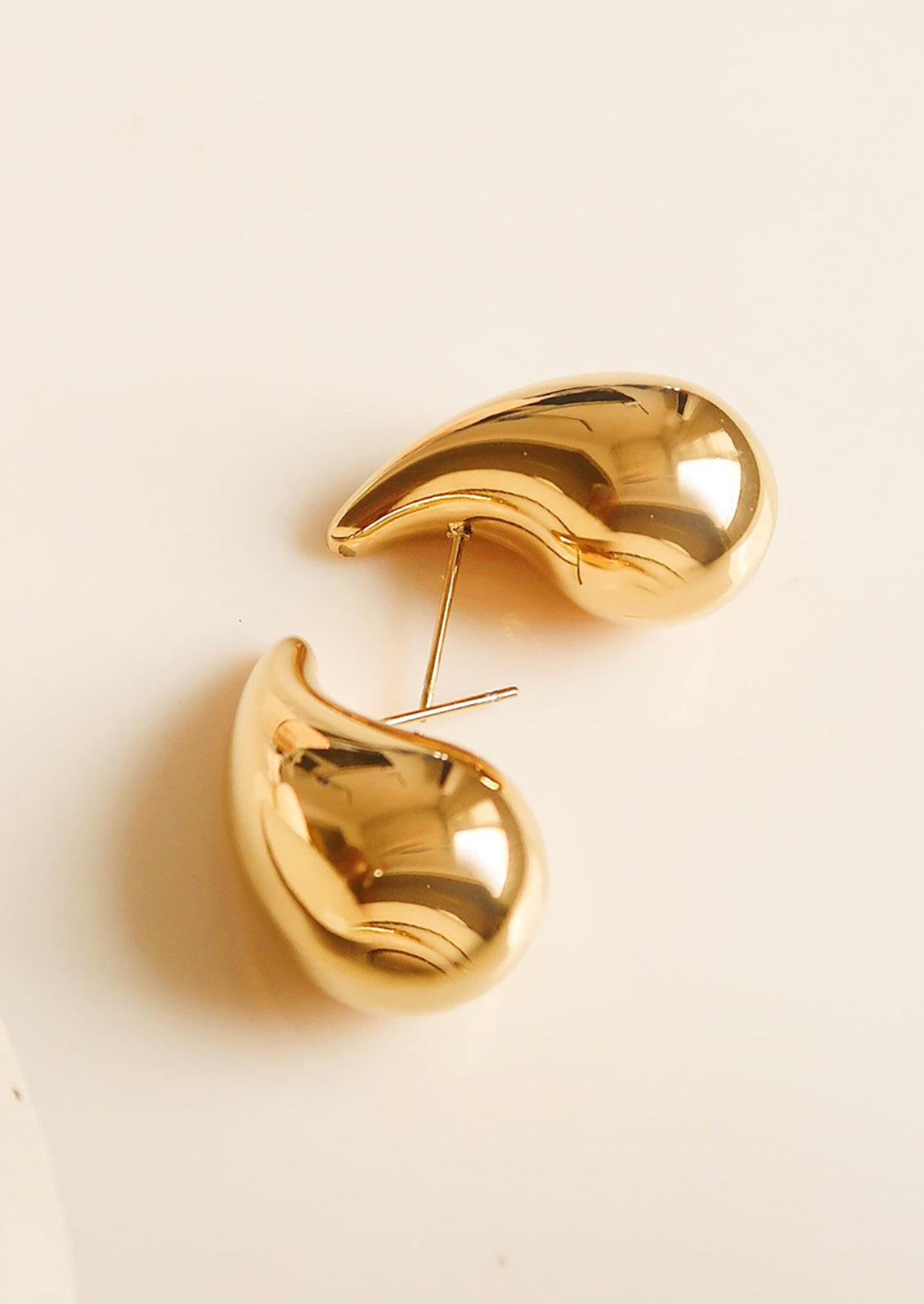 A pair of chunky, teardrop-shaped earrings in gold.