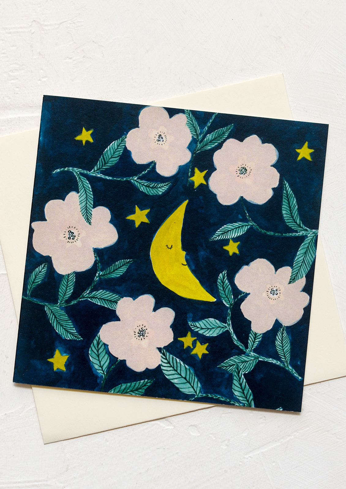 A card with illustration of crescent moon amidst pink flowers.