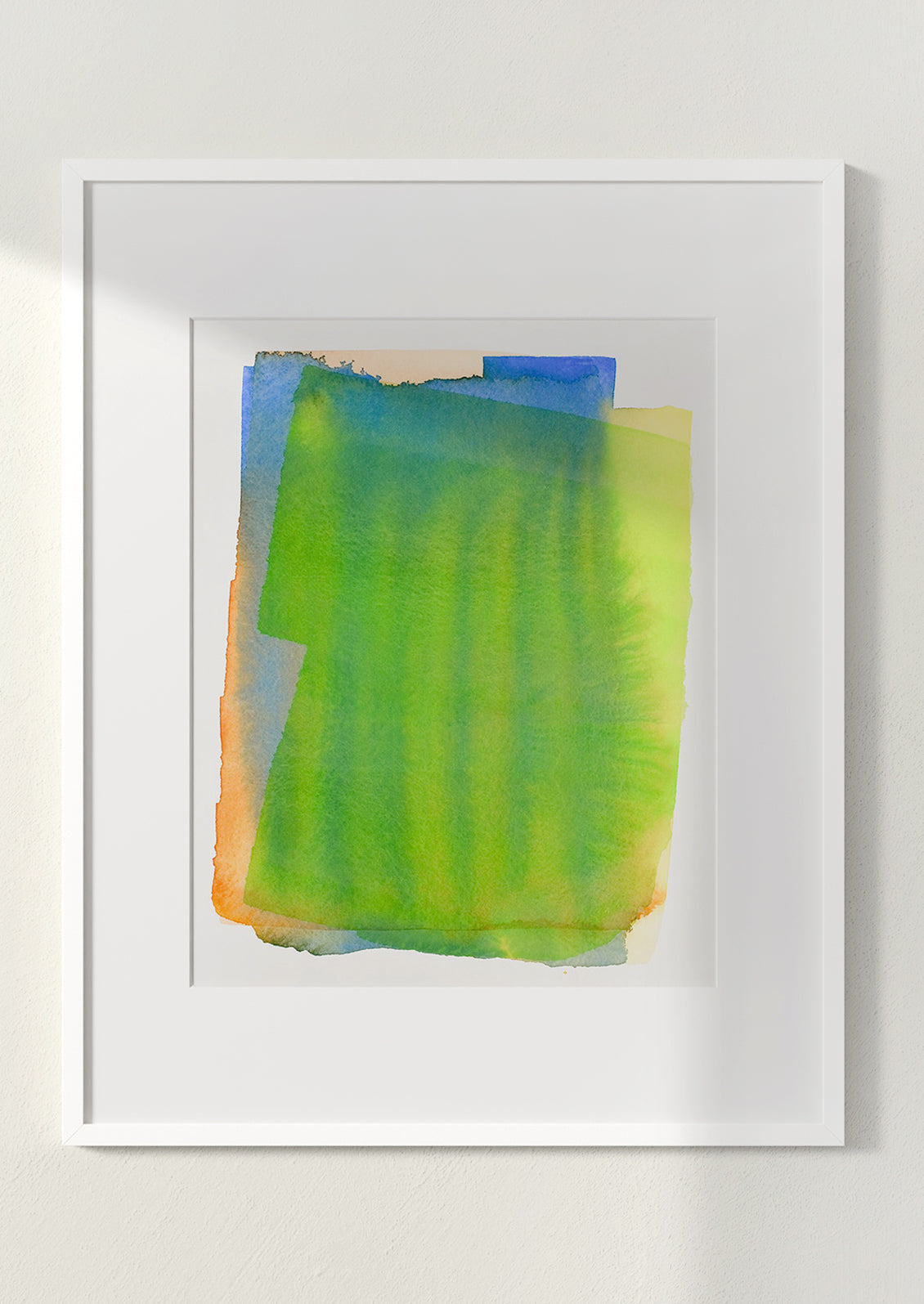 Art print of a watercolor abstract form in green, yellow, blue and orange, in white frame.