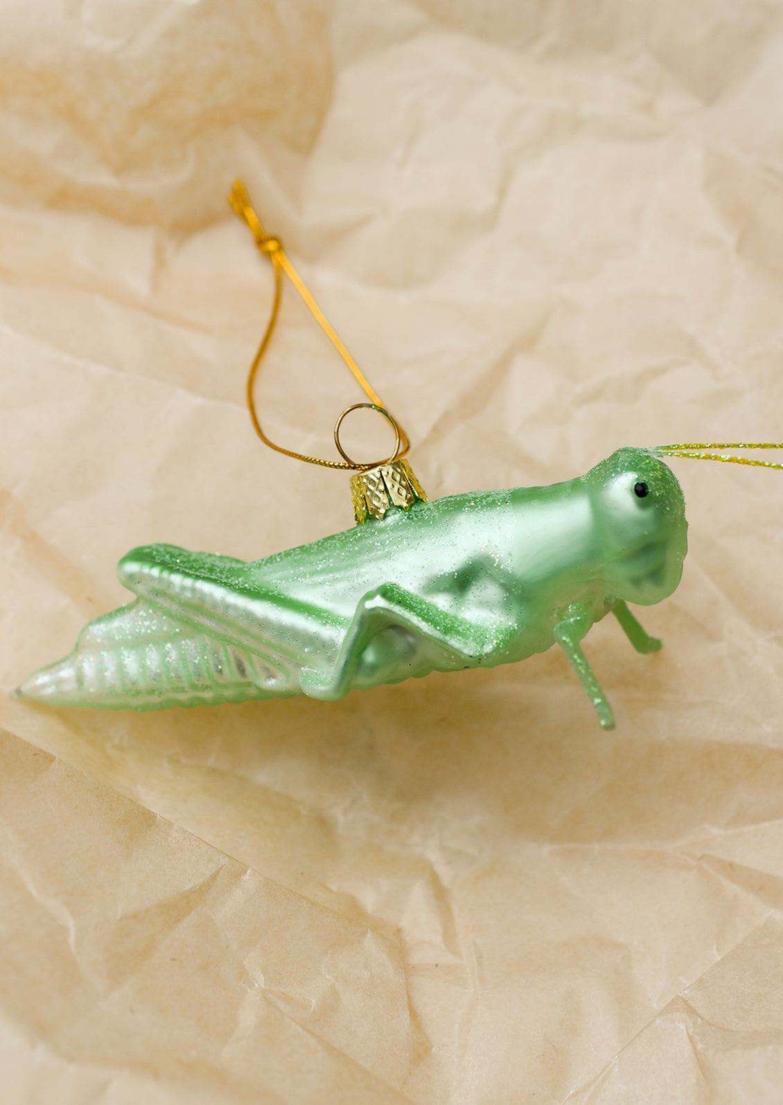 A glass ornament of light green grasshopper.