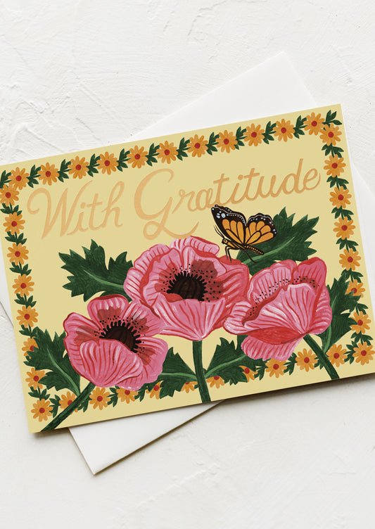 A yellow floral print card with large gold text reading "With gratitude".