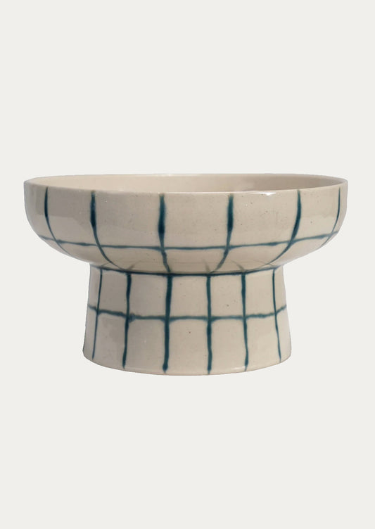 A footed pedestal bowl in natural ceramic with blue painted grid pattern.