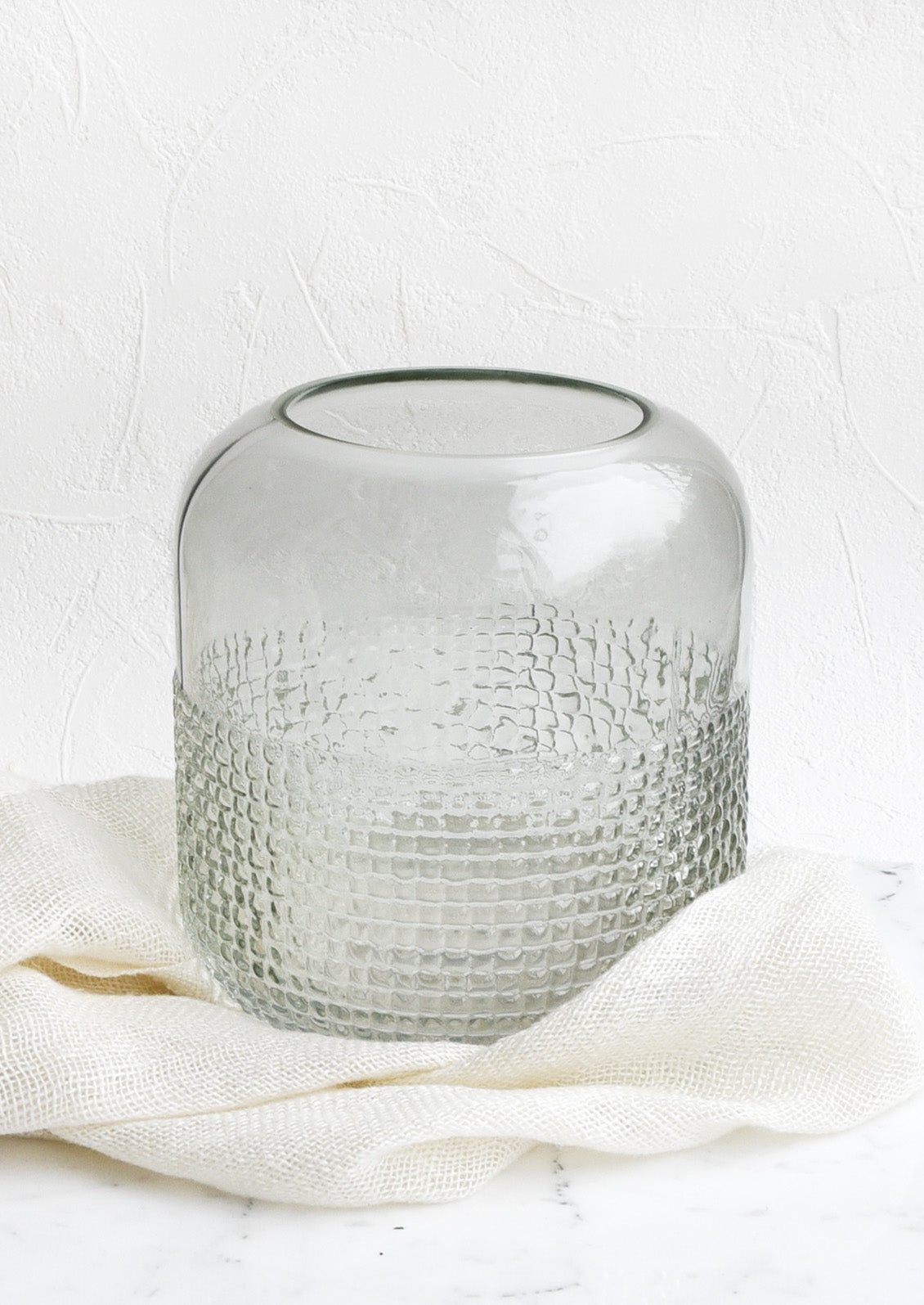 A glass vase with pyramid grid texture on lower half.