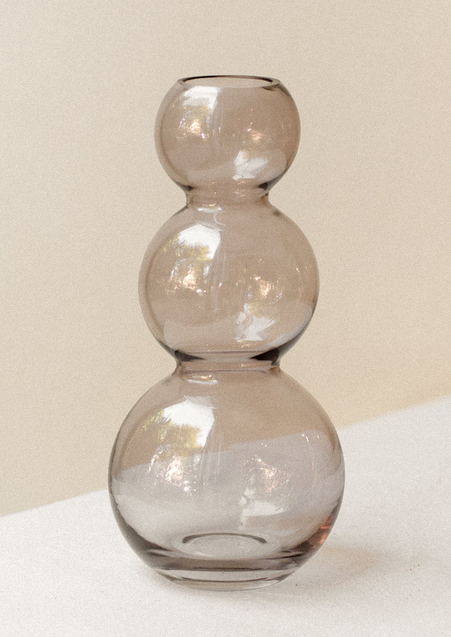 A glass vase in transparent smoky lavender color, showing off stacked round form.