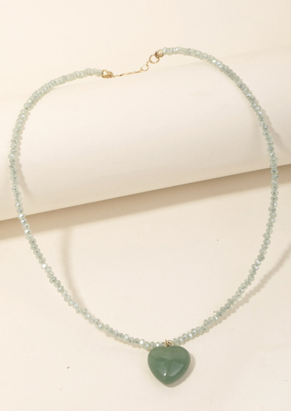 A mint green beaded crystal necklace with jade stone heart charm.