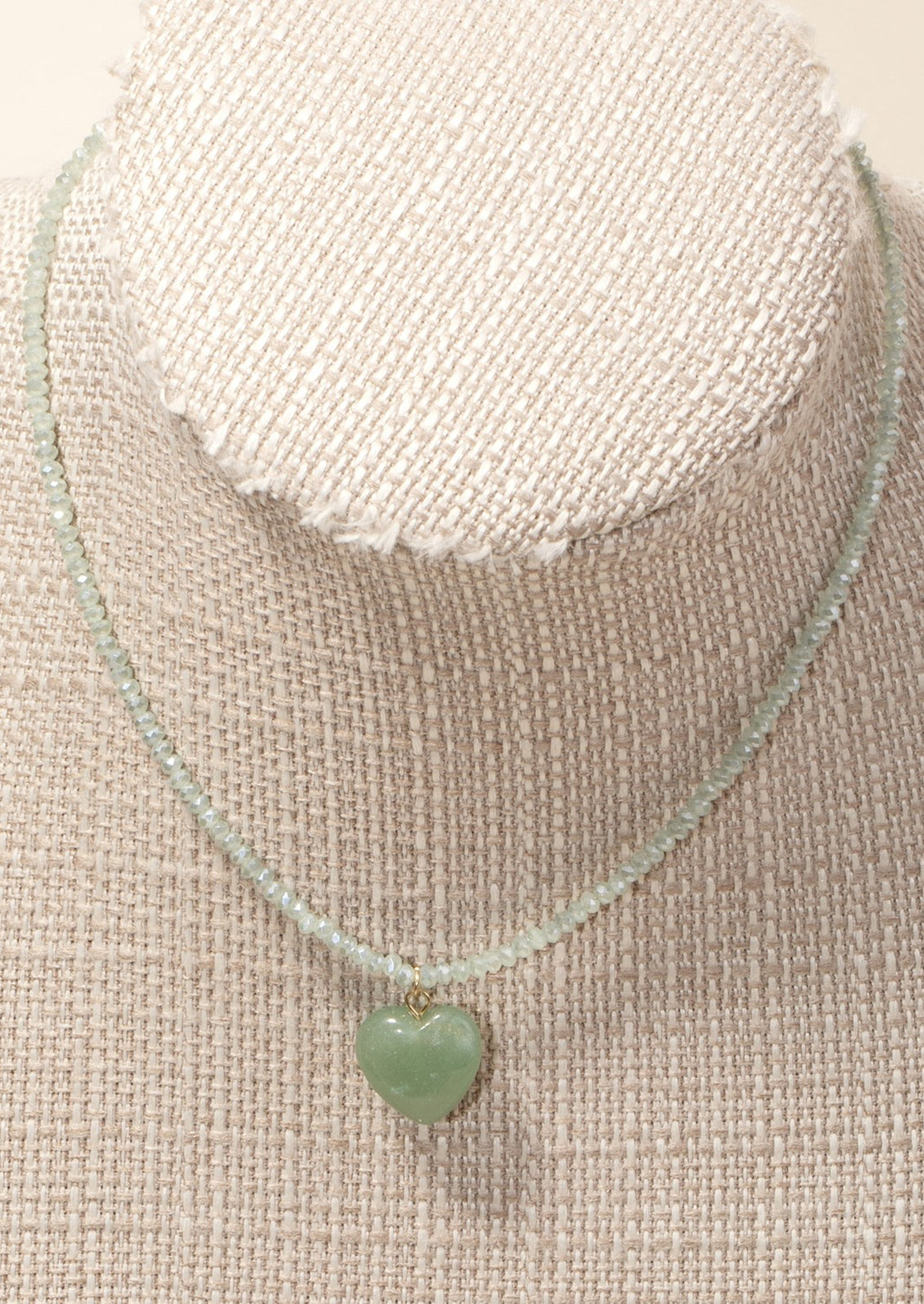 A beaded crystal necklace with heart charm on mannequin.