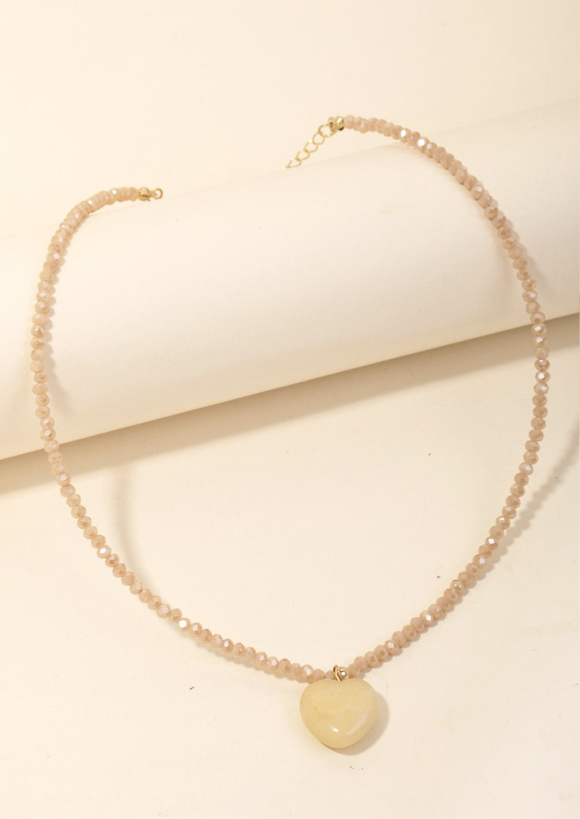 A tan beaded crystal necklace with tan stone heart charm.