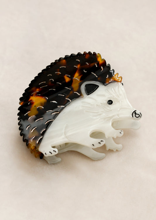 A hair claw in the shape of a hedgehog in white and brown.