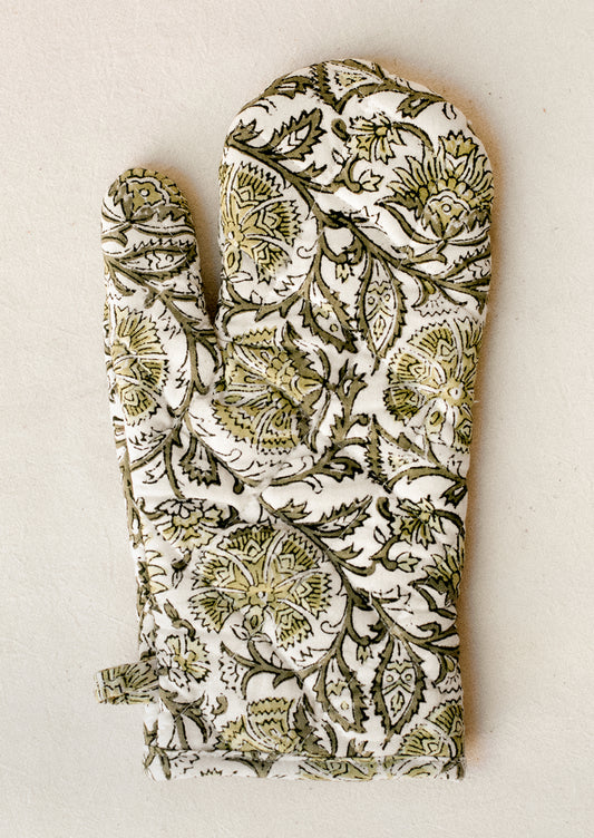 A quilted cotton oven mitt in green floral block print pattern.