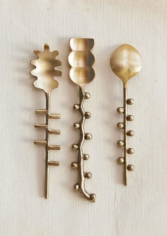 Three different shaped canape spoons in brass.