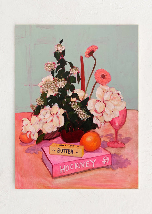 A brightly colored still life painting of orange, stick of butter, flowers on hockney art book.